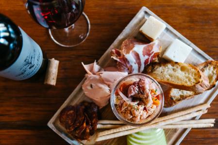 an uncorked bottle of wine and a glass of red win accompany a charcuterie board at Bin22 wine bar