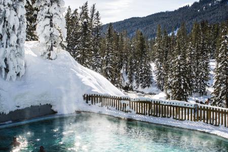 steam rises up off of a hot spring surrounded by snow at Astoria Hot Springs