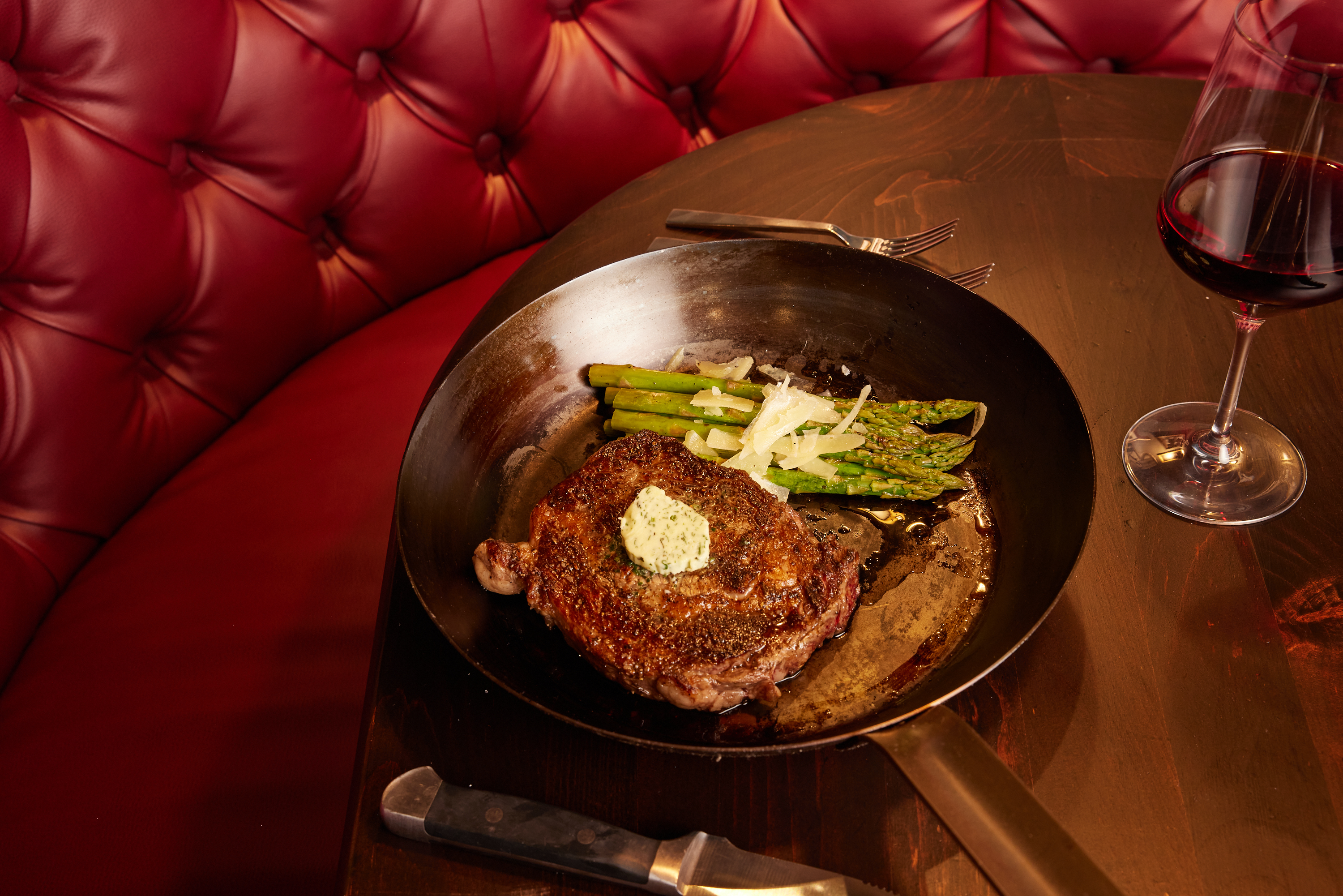 a steak and asparagus dinner served with a glass of red wine at Million Dollar Cowboy Steakhouse