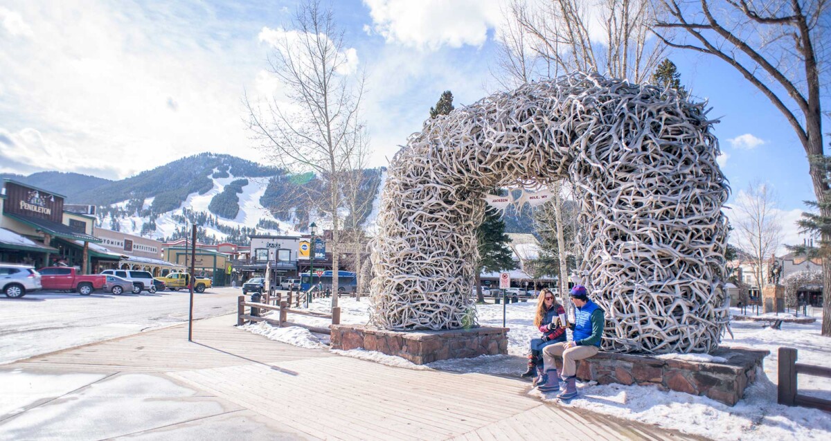 people sit in front of the arches at Town Square in Jackson Hole during winter