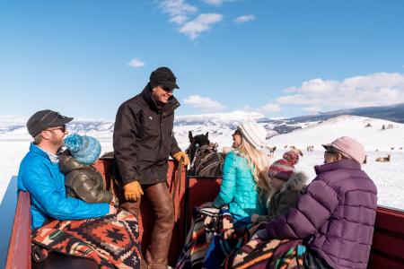 Families sit on a horse-drawn sleigh that rides through the snowy grounds of the National Elk Refuge in Jackson Hole, WY