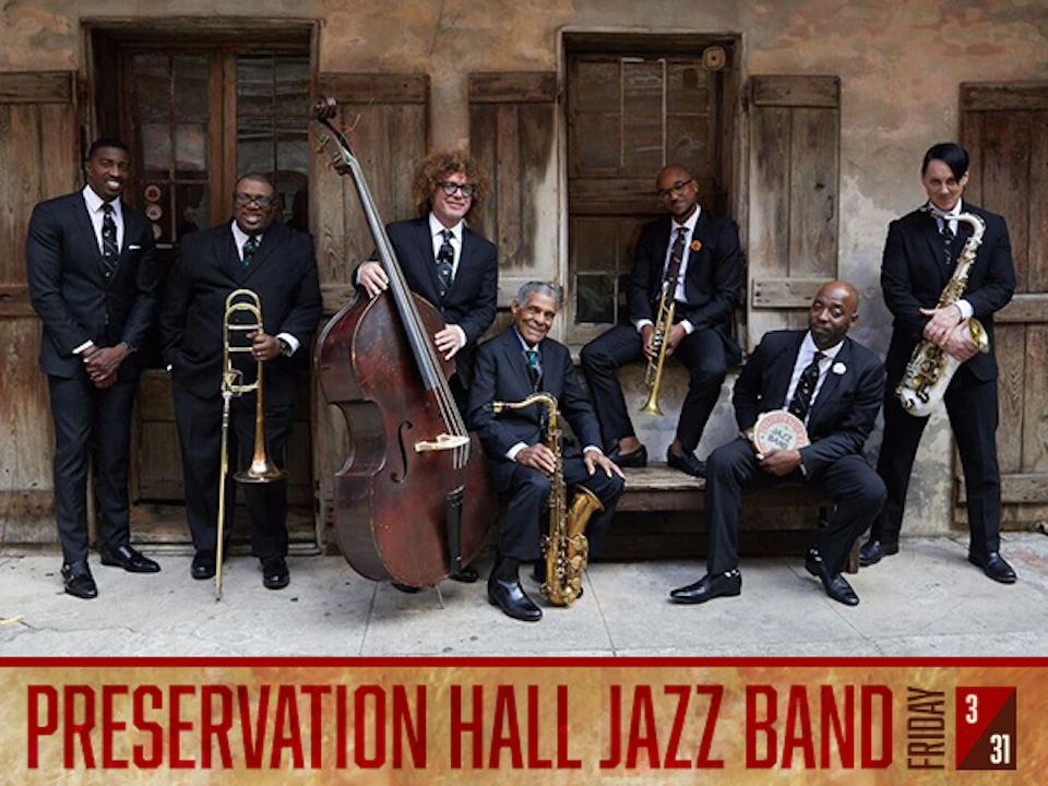 members of Preservation Hall Jazz Band holding a variety of woodwind, string and percussion instruments