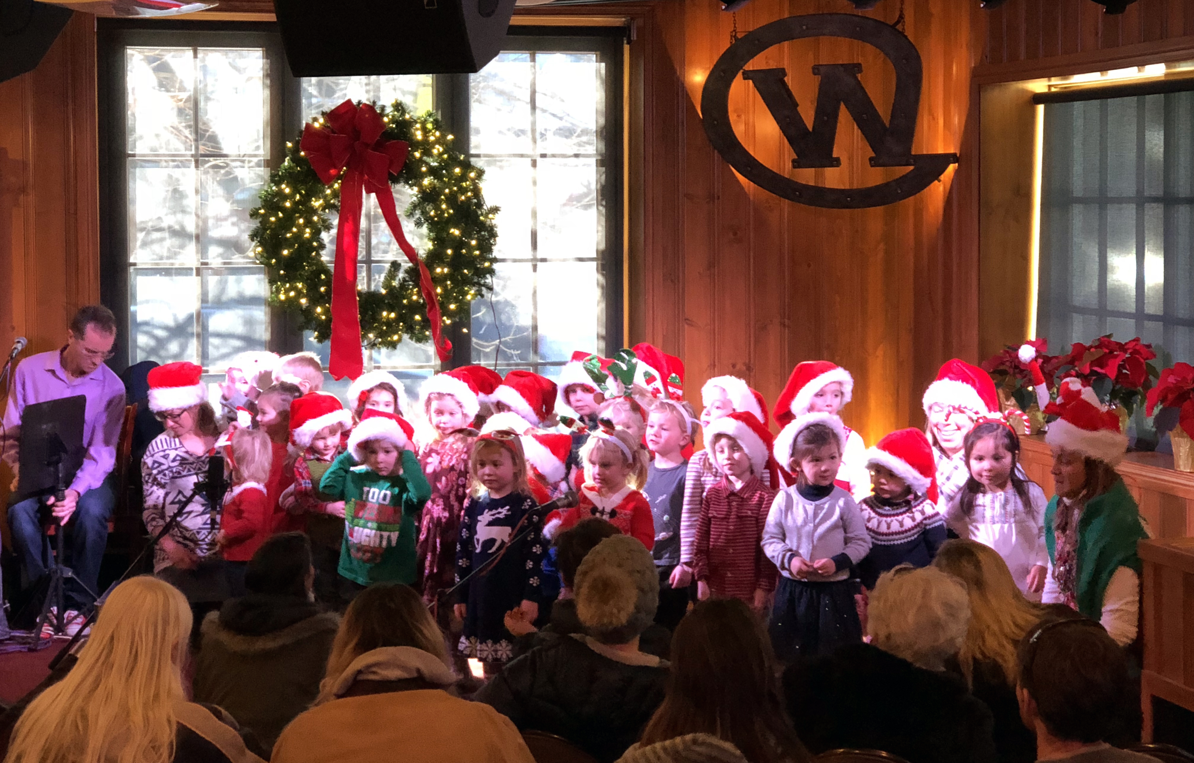 a group of preschoolers wearing red santa hats sing carols at the Silver Dollar Showroom