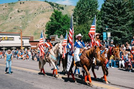 Group of people on horses holding American flags at the 4th of July Parade in Jackson Hole, WY