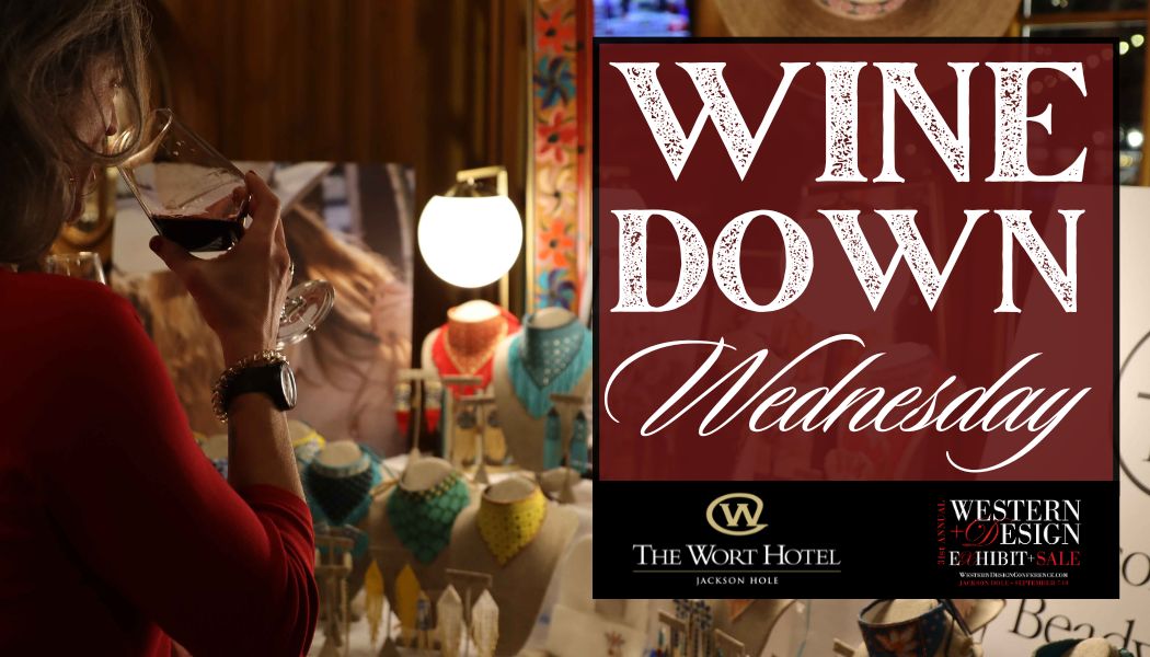 The Wine Down Wednesday event with a person sipping on a glass of red wine by a display of local jewelry.