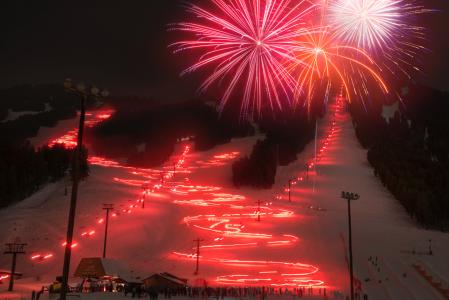 red and white fireworks fill the night sky at the Torchlight Parade and Fireworks in Jackson Hole on NYE